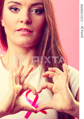 Breast cancer. Woman making heart shape on pink ribbon 120140606