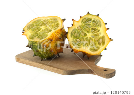 Fresh kiwano or spiked melon sliced open on a wooden board isolated on white background Fresh kiwano or spiked melon sliced open on a wooden board isolated on white background 120140793