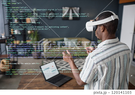 Young Black man wearing VR headset standing in living room using virtual app for coding 120141103