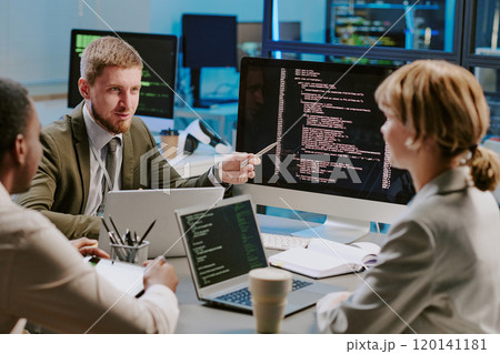 Group of three young data security specialists discussing ways of upgrading computer systems during meeting in modern office Group of three young data security specialists discussing ways of upgrading computer systems during meeting in modern office 120141181