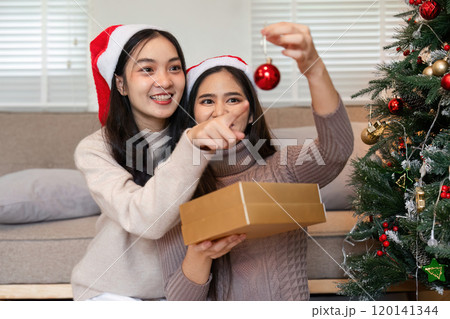 Festive Family Moment: Couple and Young Woman Joyfully Decorating Room for Christmas with Ornaments and Holiday Spirit Festive Family Moment: Couple and Young Woman Joyfully Decorating Room for Christmas with Ornaments and Holiday Spirit 120141344