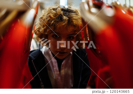 young attractive red-haired woman choosing red clothes in boutique 120143665