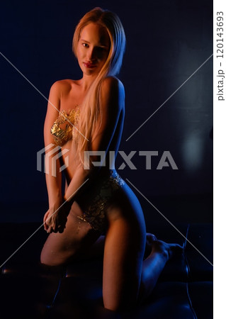 Elegant model showcasing golden attire in a dramatic lighting setup at night 120143693
