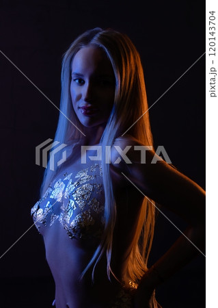 A striking silhouette of a model in shimmering fashion under dramatic lighting A striking silhouette of a model in shimmering fashion under dramatic lighting 120143704