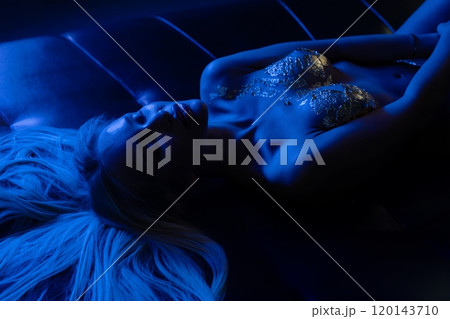 A model lounges under blue lights showcasing a creative fashion concept 120143710