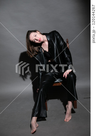 Portrait of a beautiful slender woman 40 years old sitting on an armchair Portrait of a beautiful slender woman 40 years old sitting on an armchair 120144267