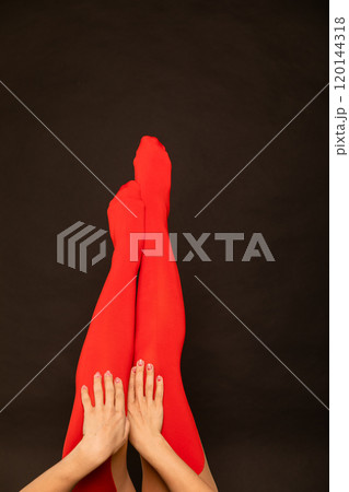 Beautiful female legs in red tights stockings on a black background 120144318