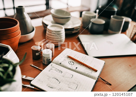 A designers dream. Cropped shot of a potters sketches in a notebook on a work desk in her workshop. A designers dream. Cropped shot of a potters sketches in a notebook on a work desk in her workshop. 120145107