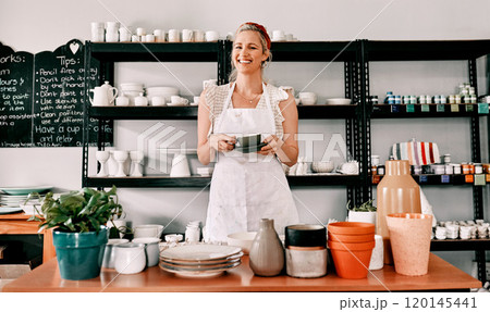 Coffee and pottery go hand in hand. Cropped portrait of an attractive mature woman standing alone and holding a cup of coffee in her pottery workshop. 120145441