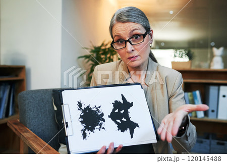 What you see says a lot. Portrait of a mature psychologist holding up an inkblot test during a therapeutic session. 120145488