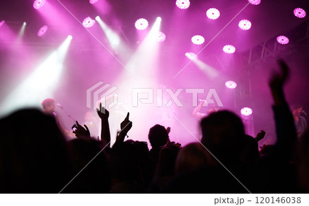 Lighting up you night. Rearview of an audience with hands raised at a music festival and lights streaming down from above the stage. 120146038