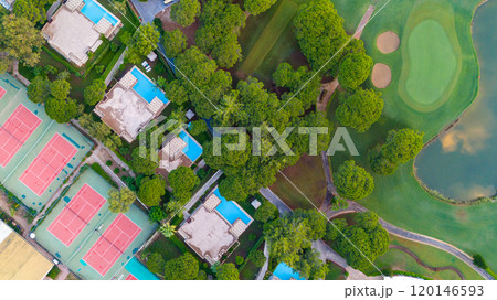 Scenic top-down view of a resort complex featuring villas, swimming pools, and tennis courts amid a tranquil natural setting. Scenic top-down view of a resort complex featuring villas, swimming pools, and tennis courts amid a tranquil natural setting. 120146593