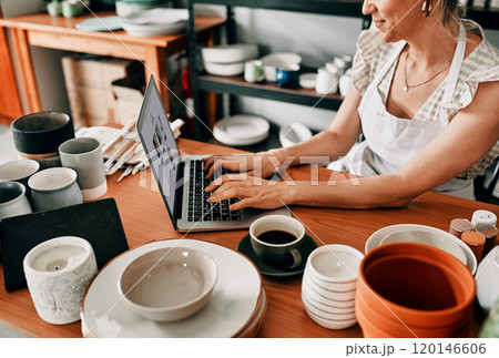 Replying to customer emails. Cropped shot of an attractive mature woman sitting alone and using her laptop in her pottery workshop. 120146606
