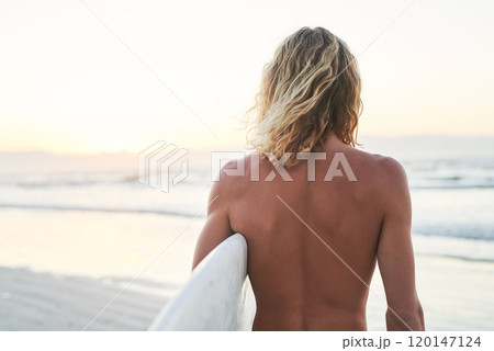 Back to the beach where I belong. Rearview shot of a young surfer looking at the ocean waves before going surfing at the beach. 120147124