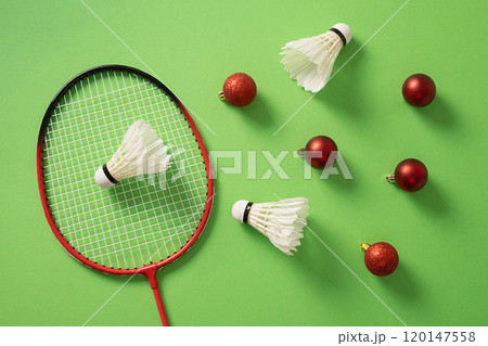 Christmas concept with badminton racket, red balls and white feather badminton shuttlecocks on green background. View from above. Xmas greeting card. Christmas concept with badminton racket, red balls and white feather badminton shuttlecocks on green background. View from above. Xmas greeting card. 120147558