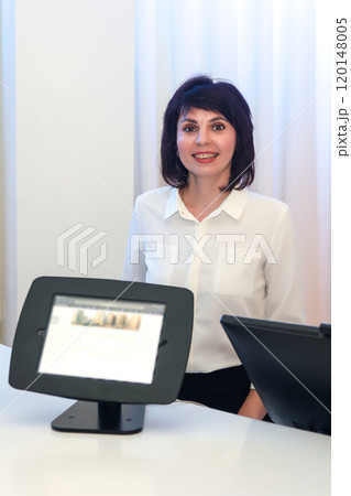 Woman at the hotel counter greeting and guiding guests to their hotel rooms Woman at the hotel counter greeting and guiding guests to their hotel rooms 120148005