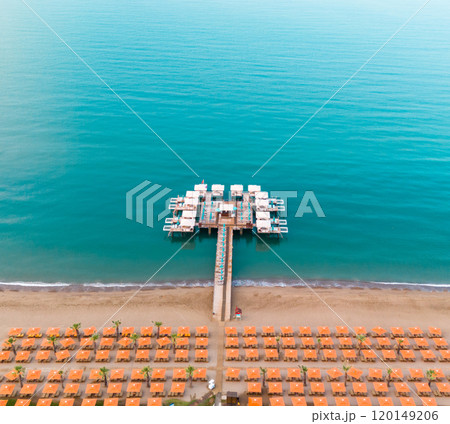 A beautiful aerial view of a luxurious beach resort pier extending into the turquoise sea with rows of inviting cabanas and umbrellas A beautiful aerial view of a luxurious beach resort pier extending into the turquoise sea with rows of inviting cabanas and umbrellas 120149206