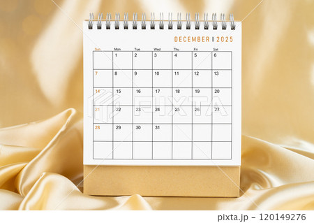 Front view of December 2025 desk calendar on gold silk. Front view of December 2025 desk calendar on gold silk. 120149276