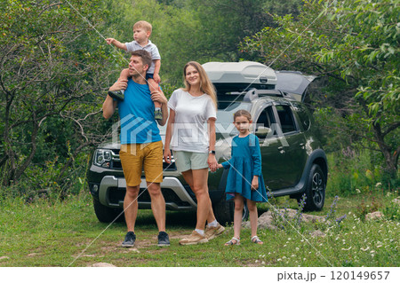 A happy family is enjoying a fun outdoor adventure together with their SUV surrounded by lush green landscapes A happy family is enjoying a fun outdoor adventure together with their SUV surrounded by lush green landscapes 120149657