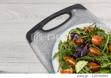Vegetable salad of tomatoes, cucumbers, greens with sesame on the plate. 120149905