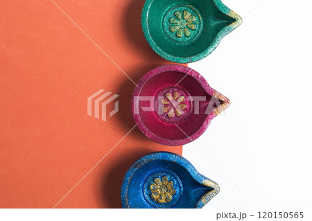 Colorful Diwali Diyas on a vibrant orange and white background for the festival of lights Colorful Diwali Diyas on a vibrant orange and white background for the festival of lights 120150565
