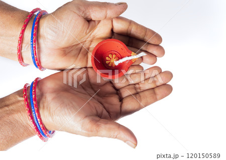 Top view of Indian woman's hands holding Diwali Diya on white background Top view of Indian woman's hands holding Diwali Diya on white background 120150589