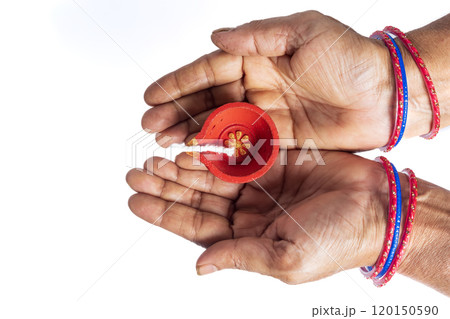 Top view of Indian woman's hands holding Diwali Diya on white background 120150590