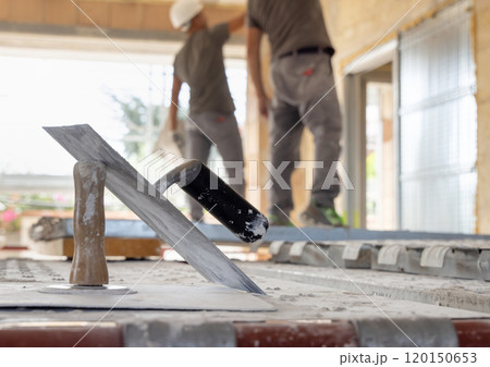 Craftsmen in grey clothes working inside a room standing on scaffoldings during construction Craftsmen in grey clothes working inside a room standing on scaffoldings during construction 120150653