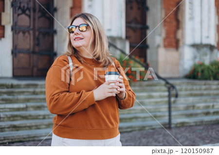 Happy young 30s Woman holding eco paper cup of coffee on urban background, Coffee to go on the city street. Food, rest, Take away concept. 120150987