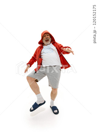 Pensioner, dressed red jacket, shorts and slippers dancing raising legs against white studio background. Excited mature man. Pensioner, dressed red jacket, shorts and slippers dancing raising legs against white studio background. Excited mature man. 120152175