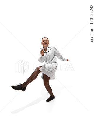 Young woman, dressed as doc, dancing rising hands and legs, showing willingness to help people against white studio background. 120152242