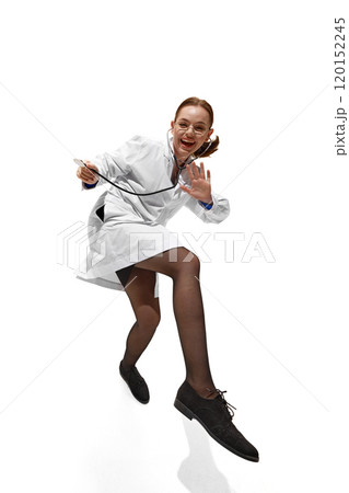 Dynamic photo of young woman, doctor in full gear, with stethoscope, dancing because she cured patient against white studio background. Dynamic photo of young woman, doctor in full gear, with stethoscope, dancing because she cured patient against white studio background. 120152245