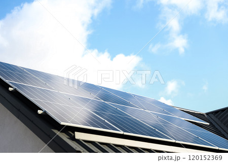 Solar panel cells on cloudy blue sky background. Clean alternative energy power concept. Modern house with solar panels stand-alone photovoltaic plant system on metal sheet roof. Go green 120152369