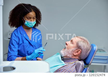 Dentist carefully administers injection, keeping professional yet comforting approach to ease patient's anxiety. 120152474