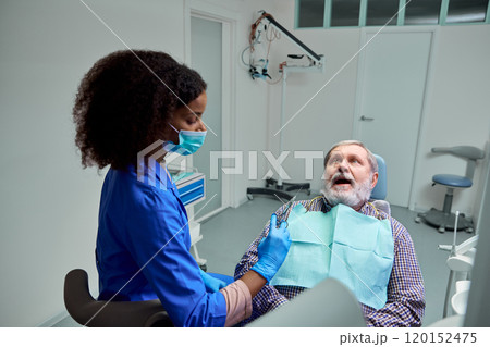 Dentist explains anesthesia effects, helping mature man, patient feel calm and ready for procedure. 120152475