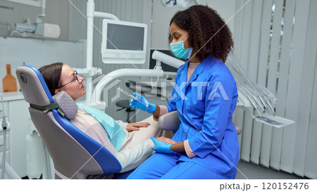 Dentist explains anesthesia effects, helping mature man, patient feel calm and ready for procedure. 120152476