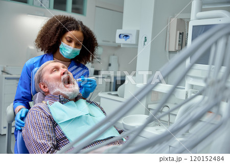 Dentist completes whitening treatment, discussing aftercare tips to help patient maintain bright, healthy smile. 120152484