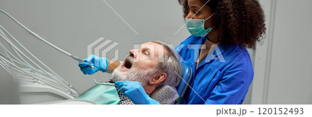 Dentist performs procedure with focused care, explaining each step to keep patient comfortable, ensuring smooth, calming experience. 120152493