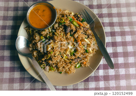 A plate of bhat bhuteko or nepali fried rice with vegetables and buffalo meat, accompanied by a small dish of spicy tomato sauce, authentic local food of Nepal 120152499
