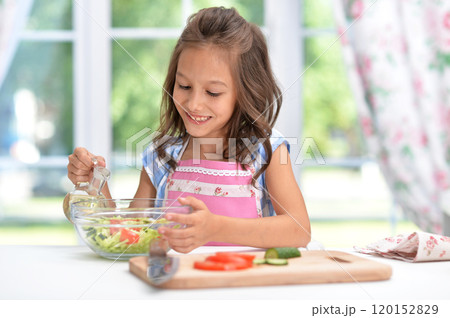 Cute happy girl coocking salad on kitchen 120152829