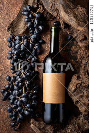 Bottle of red wine with blue grapes and old weathered snags. 120153715
