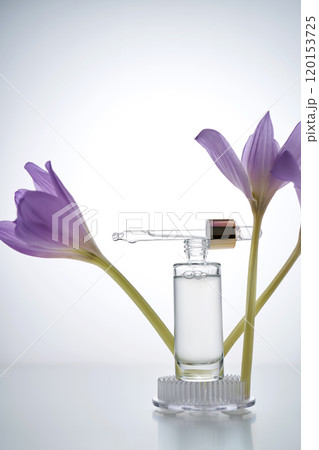 Serum bottle with dropper on light background with purple flowers. 120153725