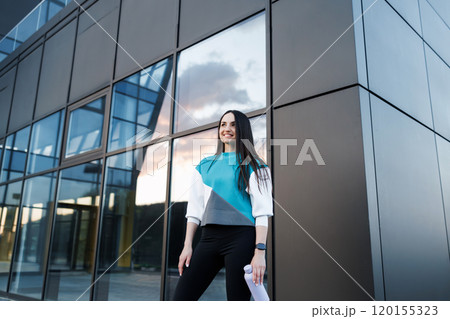 Woman holding bottle with water after morning workout. Young athletic woman standing near dark wall background after jogging Healthy lifestyle concept 120155323
