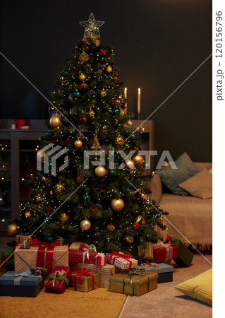 Vertical background image of decorated Christmas tree and presents in dim cozy home interior with and gold details copy space 120156796
