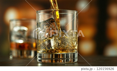 Pouring whiskey into glass full of ice cubes. Pouring whiskey into glass full of ice cubes. 120156926