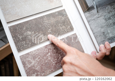 Designer hand pointing at stone tile sample on display catalog Designer hand pointing at stone tile sample on display catalog 120162062