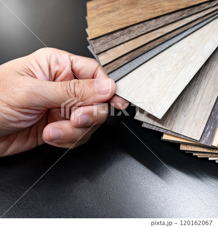 Designer hand picking sample of wood laminated material from natural collection 120162067
