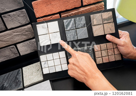 Architect hand pointing at stone tile collection display on sample board Architect hand pointing at stone tile collection display on sample board 120162081