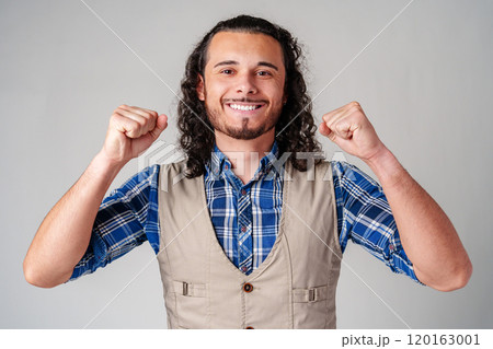 Happy man celebrating success with raised fists in a studio against a plain background 120163001
