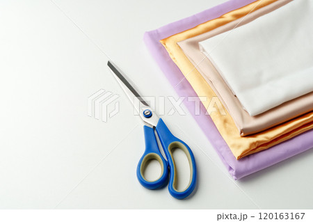 Crafting supplies arranged on a table with scissors and folded fabric in various colors 120163167